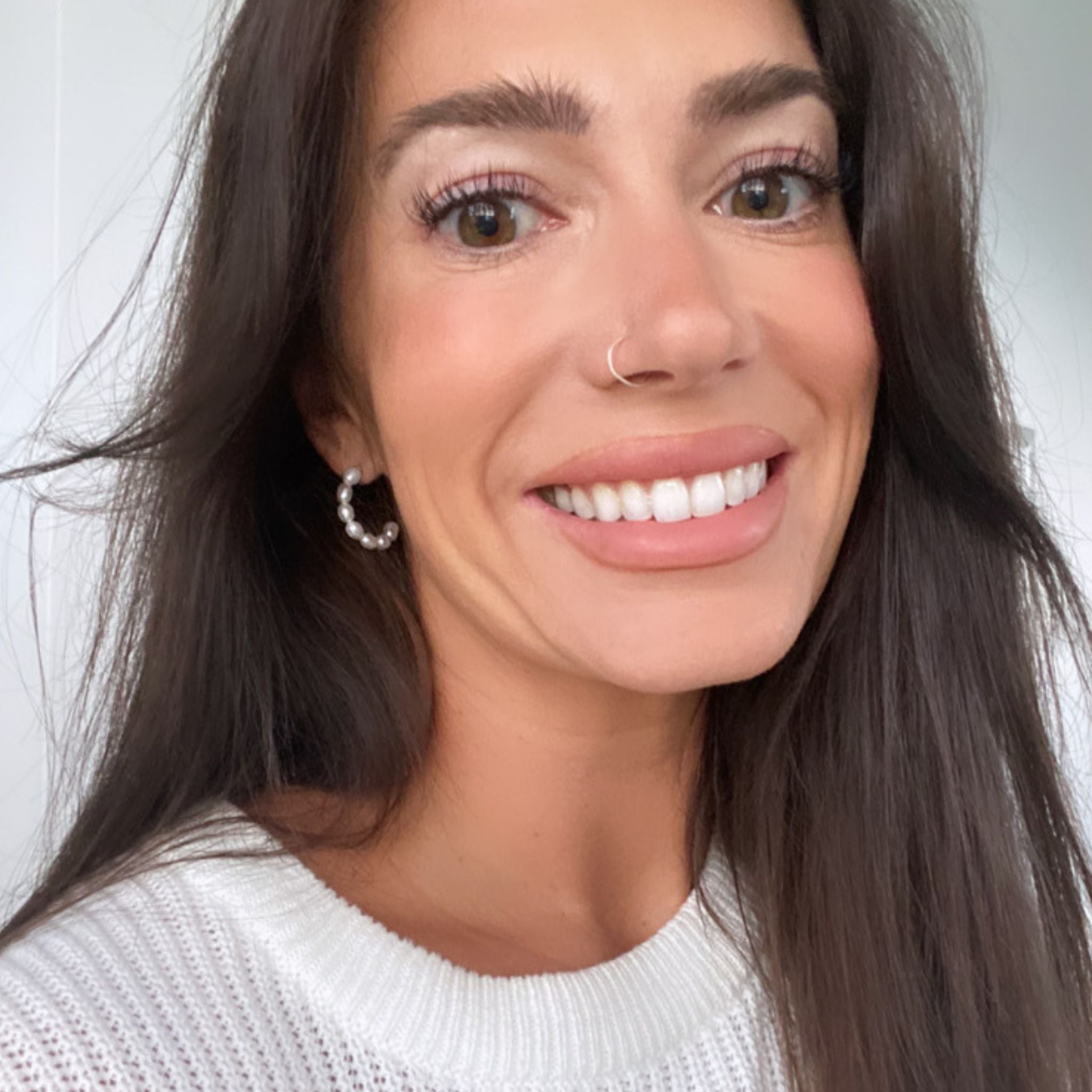 Smiling model with small pearl hoops
