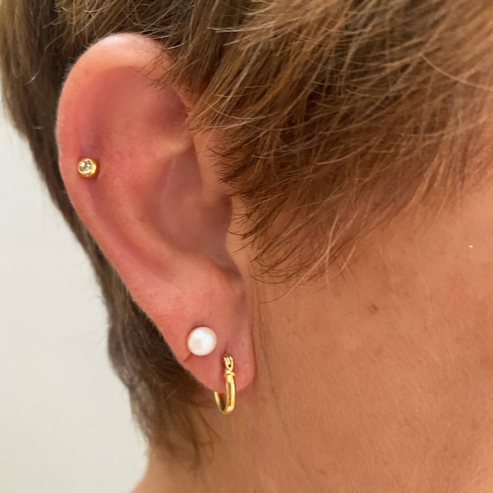 Small white pearl studs stacked with other earrings